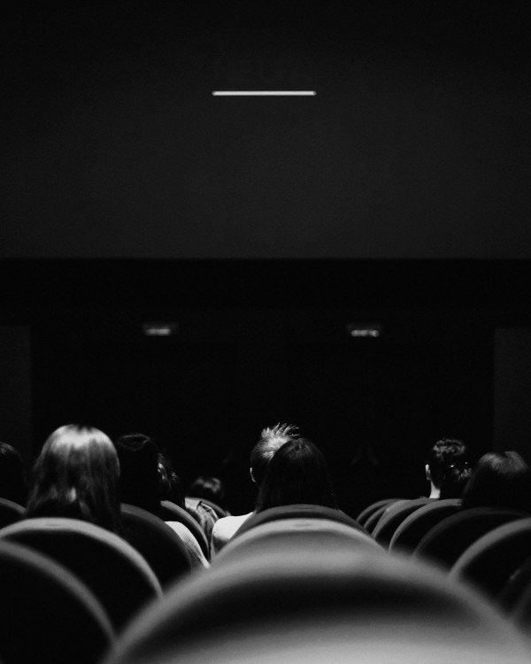 Menschen in dunklem Kinosaal blicken in Richtung Leinwand